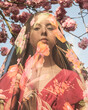 © Milou Dirks - abstract fine art spring portrait of woman covered by thin floral veil and cherry blossom tree in background