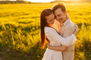 Wall Mural - portrait of smiling young couple in love standing hugging with closed eyes on beautiful green meadow