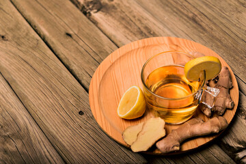 Cup of hot tea with ginger root, lemon and curcuma. Adding natural raw honey to cup of hot tea. Vitamin C drink, immune system boost.