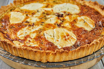 Wall Mural - Goat cheese quiche on a wooden background. French gourmet cuisine