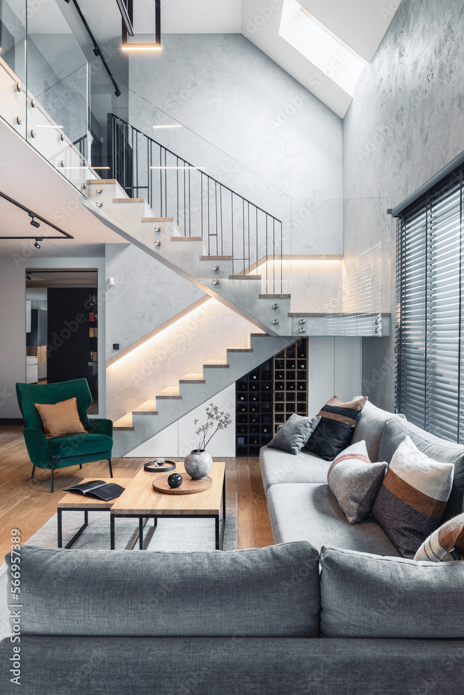 Stylish composition of stairs in living room interior. Grey sofa, green ...