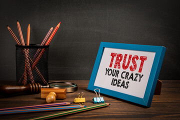 Wall Mural - Trust Your Crazy Ideas. Motivational quote. Picture frame on the office table