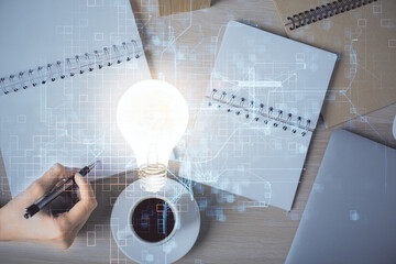 Poster - Bulb hologram over hands taking notes background. Concept of idea. Double exposure