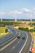 highway in a rural landscape with a wind turbine farm on the horizon
