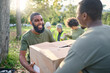 Community service, black man and giving box in park of donation, volunteering or social responsibility. Happy guy, NGO workers and helping with package outdoor of charity, support or society outreach