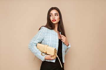 Wall Mural - Young brunette woman in blue jacket. Model posing in a business suit. Girl  with beige handbag. Fashion photo