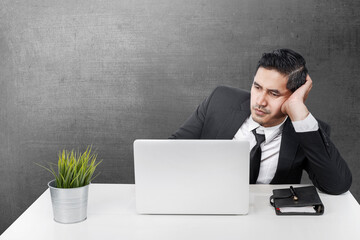 Wall Mural - Asian businessman sitting with a laptop on the desk with a tired expression