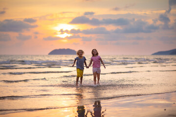 Wall Mural - Child playing on ocean beach. Kid at sunset sea.