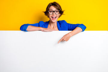 photo of impressed excited woman wear blue jacket spectacles pointing white wall poster empty space 
