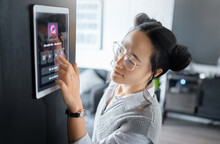 Music, tablet and Asian woman with digital system in home, apartment and living room. Technology, futuristic design and girl typing song, track and audio on ai software, biometrics and user interface