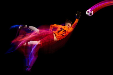 Sportive energetic man, soccer football goalkeeper in action, motion over dark background with mixed neon light. Concept of sport, achievement, competition, goals.