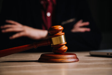 Justice and law concept.Male judge in a courtroom with the gavel, working with, computer and docking keyboard, eyeglasses, on table in morning light