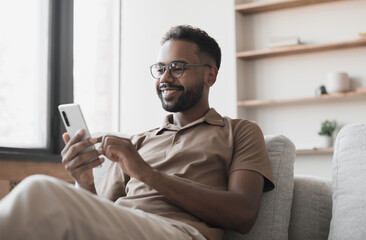young man using smartphone at home. handsome smiling men looking at mobile phone in his room. commun