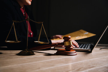 Justice and law concept.Male judge in a courtroom with the gavel, working with, computer and docking keyboard, eyeglasses, on table in morning light