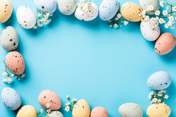 Wall Mural - Overhead shot of Easter composition with spring flowers and colorful quail eggs over blue background. Springtime and Easter holiday concept with copy space. Top view