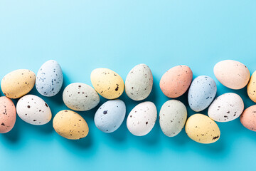 Wall Mural - Overhead shot of Easter quail eggs over blue background. Spring holidays concept with copy space. Top view