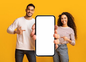 Poster - Nice Offer. Smiling Middle Eastern Couple Pointing At Big Blank Smartphone