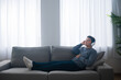 © Egoitz - Hispanic teenager boy listening to relaxing music on couch.