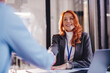 © kerkezz - a young woman smiling and shaking hands with a client, after concluding a contract