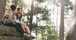 © Nicholas F/peopleimages.com - Nature, hiking and a couple relax on adventure trail in forest and sitting on a rock. Health, happy man and woman pointing at natural landscape while relaxing in woods with trees, fitness and freedom