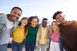 © CarlosBarquero - Leisure time with happy friends. Young people hugging and smiling taking a selfie looking at the camera. Group of multicultural boys and girls having fun outdoors celebrating vacations together.