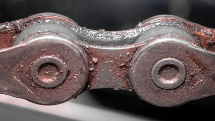 Inner part of a bicycle chain covered in dirt, grease and debris. Partially worn bicycle chain, macro close up photo of one link.