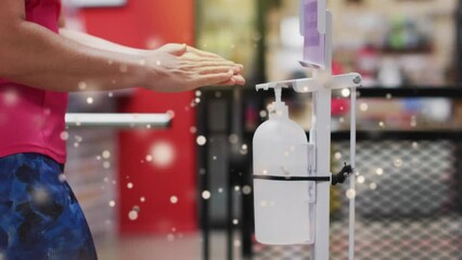 Poster - Animation of light spots over african american woman disinfecting hands, slow motion