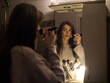 © nikitaat - young woman doing make-up in a bathroom without electricity by candlelight
