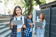 © NanSan - Attractive asian college student using laptop and tablet studying with group of friends together with english language classroom, social media and education concept.