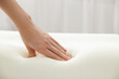 © New Africa - Woman touching orthopedic memory foam pillow indoors, closeup. Space for text