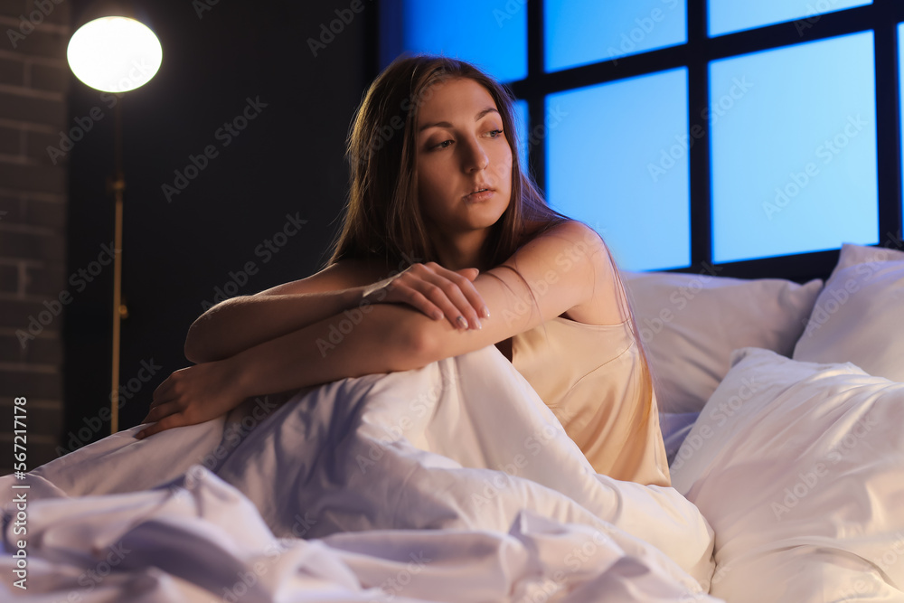 Beautiful woman sitting on bed at night