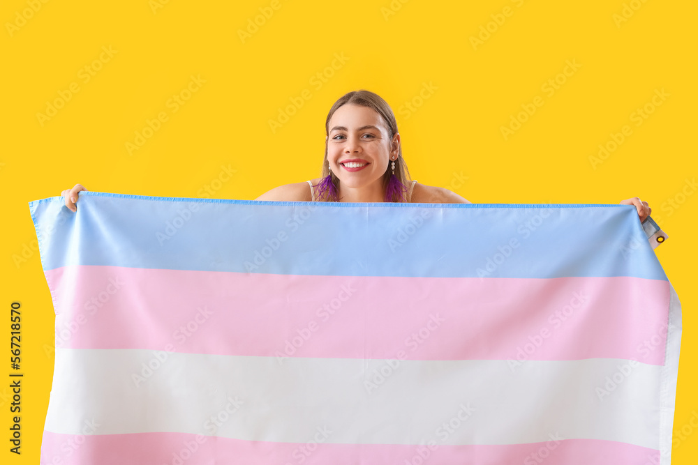 Young woman with transgender flag on yellow background