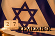 Calendar with date 27 JANUARY, word REMEMBER and burning candles on flag of Israel. International Holocaust Remembrance Day