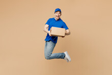 Full Body Side View Delivery Guy Fun Employee Man Wear Blue Cap T-shirt Uniform Workwear Work As Dealer Courier Jump High Hold Cardboard Box Isolated On Plain Light Beige Background. Service Concept.