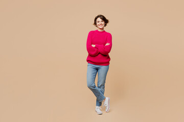 Wall Mural - Full body smiling cheerful happy caucasian young woman wear pink sweater hold hands crossed folded look camera isolated on plain pastel light beige background studio portrait People lifestyle concept