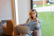 © LIGHTFIELD STUDIOS - blonde freelancer with wavy hair talking on smartphone while using laptop in cafe.