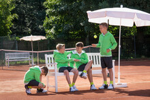 Group Of Young Boys Relaxing On Tennis Court, Bavaria, Germany