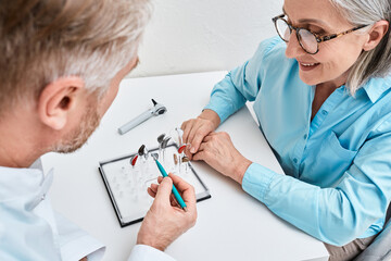 Wall Mural - Hearing aids. Behind-The-Ear hearing aids are recommended by audioprosthetist to his woman patient because it is best hearing solutions