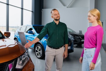 The sales manager offers a young woman options for buying a new car in the showroom. Successful businesswoman