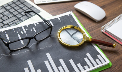 Wall Mural - Eyeglasses, magnifying glass, financial graphs on the table.