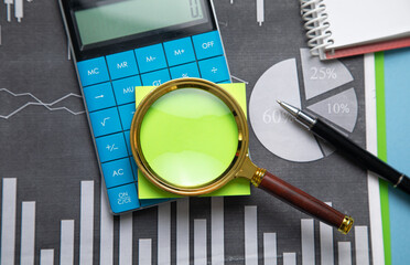 Sticker - Magnifying glass with a sticky note on financial graphs.