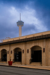 Wall Mural - Dramatic blue winter storm clouds over the Alamo Street with partial skyline view of the Tower of Americas in Texas, USA