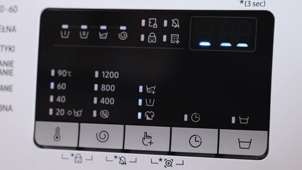 Cropped shot of hand pushing sensor buttons on display of modern washing machine. Close up of woman selecting regime and temperature on washing machine control panel