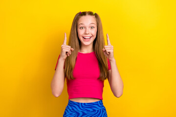 Canvas Print - Photo of nice impressed schoolgirl with straight hairstyle wear pink t-shirt indicating empty space isolated on yellow color background