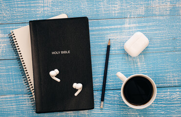 Wall Mural - Bible, notebook, earphones and coffee cup on blue wooden background, flat lay, copy space.