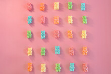 Styled Bulk Vintage Candy. Sour Coated Rainbow Gummy Bears Lined Up On Pink Background. Valentines Day Candy Flat Lay.