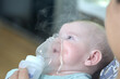 © justoomm - A sick child breathes with a nebulizer mask with a steam inhaler due to a respiratory disease. A mother holding an inhaler in her hands.