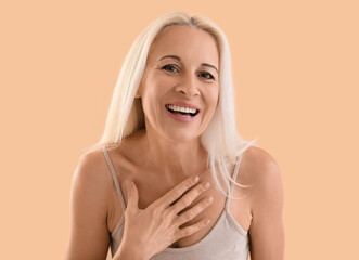 Canvas Print - Mature blonde woman smiling on beige background