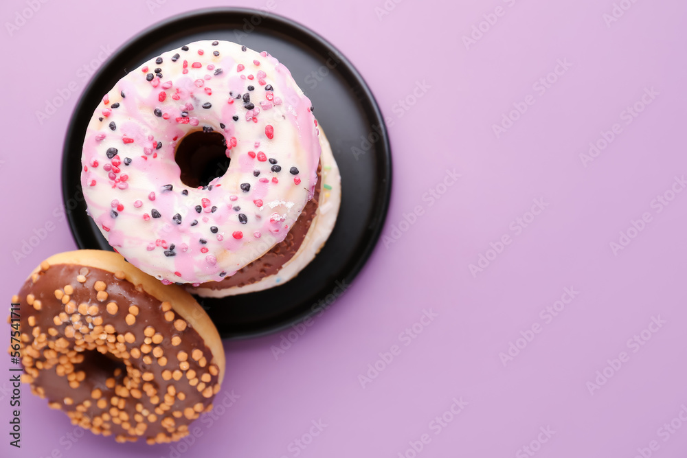 Plate with sweet donuts on lilac background