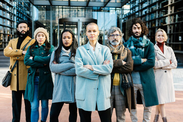 Successful group portrait of diverse business people standing at company entrance. Confident businesswoman boss leading businesspeople team with folded hands at corporate office outdoors. Teamwork